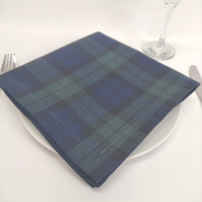 Guardanapo de tecido azul e verde com padrão tartan sobre prato branco