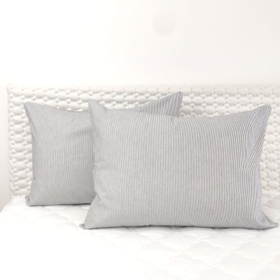 Três almofadas cinzentas às riscas sobre colchão branco acolchoado