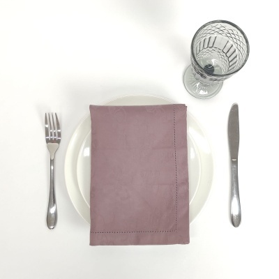 Conjunto de mesa com garfo, faca, copo de vidro, prato branco e guardanapo cor de rosa