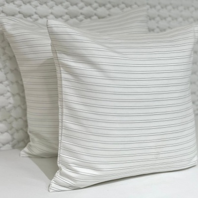 Duas almofadas brancas com riscas finas horizontais sobre superfície clara