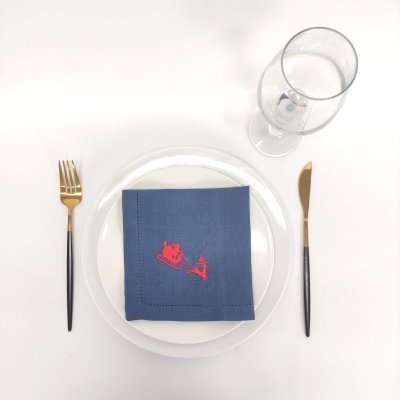 Conjunto de pratos com talheres, guardanapo azul com bordado vermelho e copo de vidro