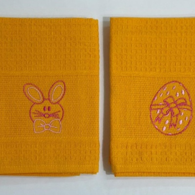 Dois panos de cozinha amarelos com bordados de coelho e ovo de páscoa