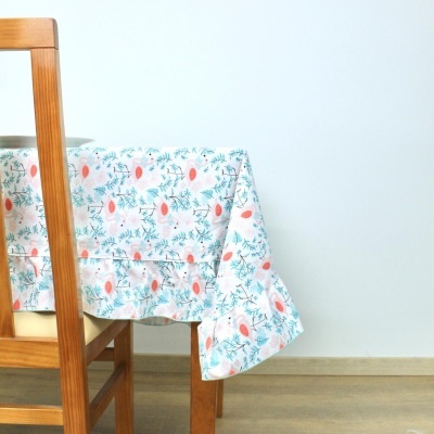 Mesa de madeira com toalha branca decorada com flores vermelhas e folhas verdes