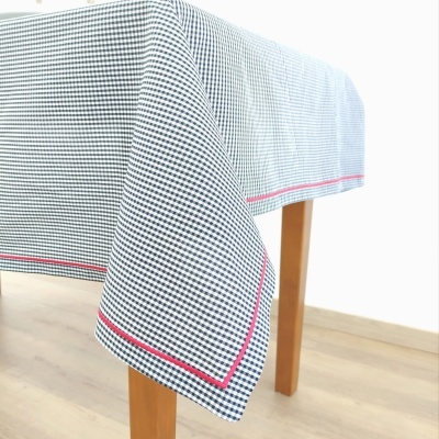 Toalha de mesa branca com xadrez preto e barra vermelha sobre mesa de madeira