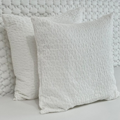 Duas almofadas brancas com textura enrugada, em fundo branco acolchoado