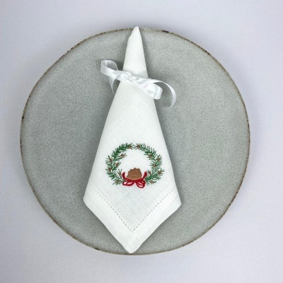 Guardanapo branco bordado com grinalda sobre prato cinzento