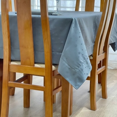 Mesa de madeira com duas cadeiras e toalha cinza com padrão de bolinhas.