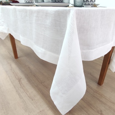 Toalha de mesa branca com bordado sobre mesa de madeira clara