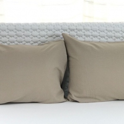 Cabeceira de cama branca texturizada com duas almofadas cinza claro