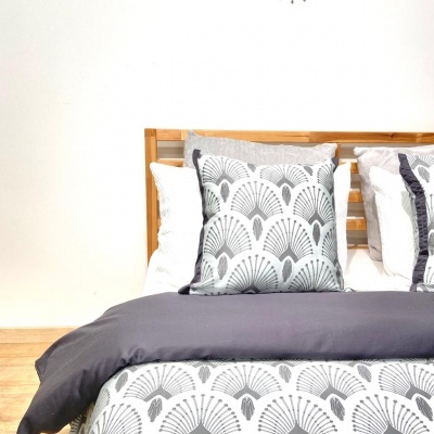 Cama com roupa de cama cinza e branca com padrão de leques em quarto minimalista