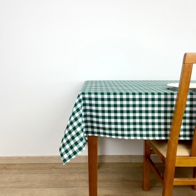 Toalha de mesa quadriculada verde e branca sobre mesa de madeira, cadeira de madeira ao lado