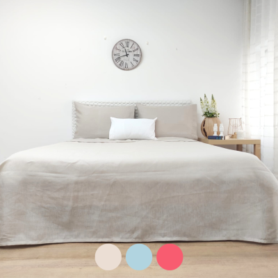 Cama com edredão cinza claro, almofadas e cabeceira trançada, relógio de parede, mesa de cabeceira com decoração