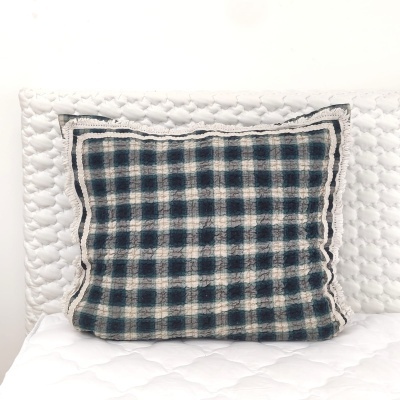 Almofada quadriculada azul, cinza e bege sobre colchão branco matelassado