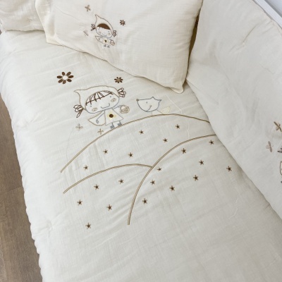 Colchão de berço creme com bordados de menina, gato, flores e estrelas em castanho