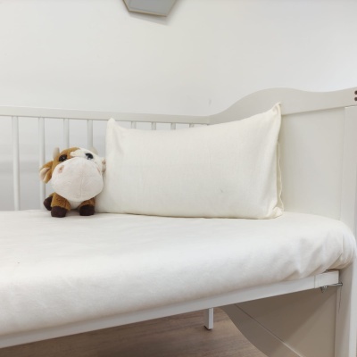 Cama de criança branca com almofada branca e peluche castanho e branco