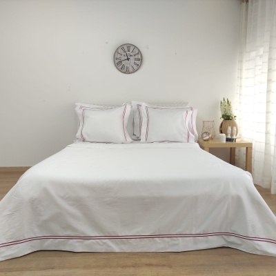 Cama de casal com roupa de cama branca com linhas vermelhas em quarto minimalista