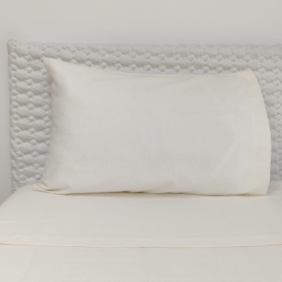 Almofada branca lisa sobre cama com cabeceira acolchoada branca