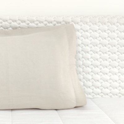 Travesseiros brancos numa cama branca com cabeceira texturizada branca