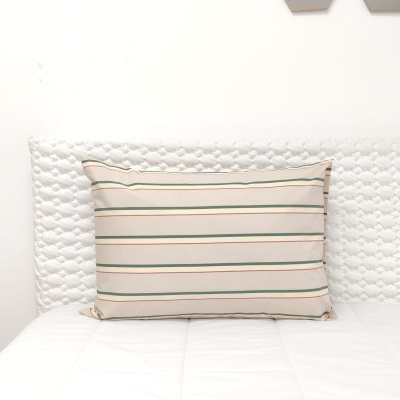 Almofada com riscas horizontais em cama branca com cabeceira acolchoada branca