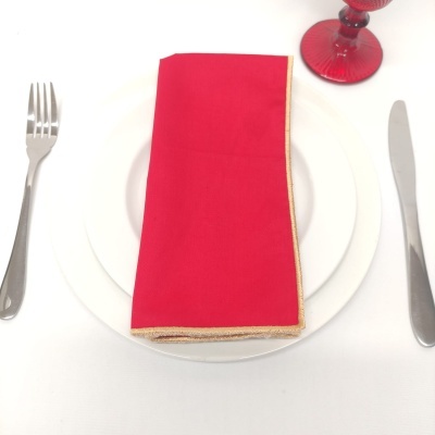 Mesa posta com prato branco, talheres, guardanapo vermelho e copo vermelho