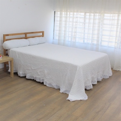 Cama de casal com colcha branca e cabeceira de madeira num quarto claro