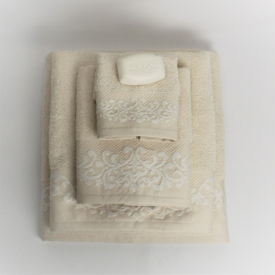 Conjunto de toalhas bege claro com padrão bordado branco e sabonete