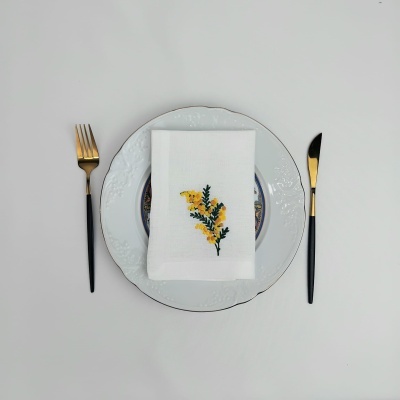 Conjunto de jantar com pratos, guardanapo bordado e talheres em fundo branco