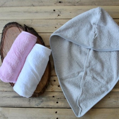 Toalhas felpudas coloridas e toalha com capuz cinzenta sobre mesa de madeira