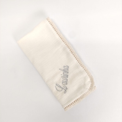 Guardanapo branco bordado com a palavra Lourinha em cinzento.