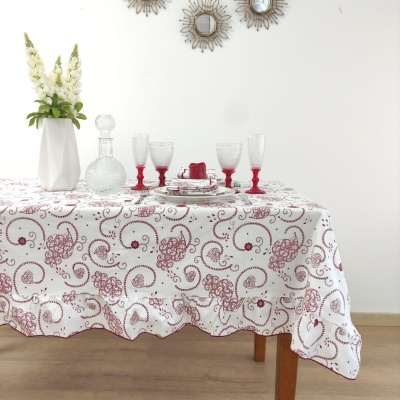 Toalha de mesa branca com padrão bordado vermelho e decoração sobre a mesa