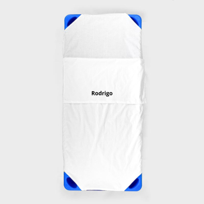 Cama pequena com lençol branco e nome 'Rodrigo'