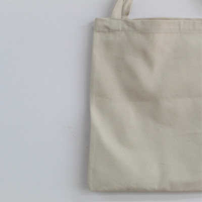 Sacola de tecido bege claro com alças sobre fundo branco