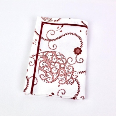 Toalha branca com padrão floral vermelho dobrada sobre fundo branco