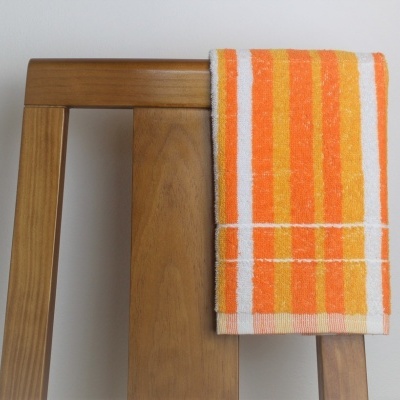 Toalha laranja e amarela pendurada numa cadeira de madeira