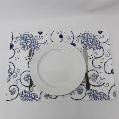 Jogo americano branco com padrão azul, prato branco, faca e garfo de metal