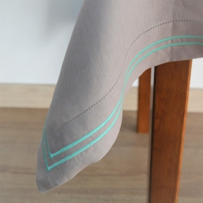 Toalha cinzenta com linhas azuis turquesa na beira de mesa de madeira