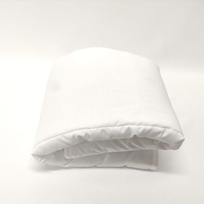 Cobertor branco dobrado sobre superfície branca.