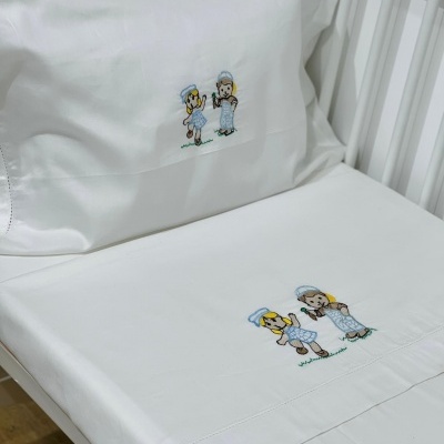 Lençóis brancos para berço com bordado de duas crianças em azul e branco