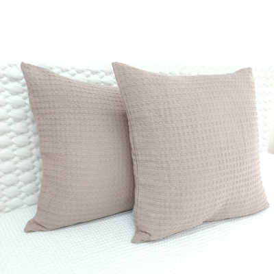 Almofadas quadradas bege com padrão texturizado sobre superfície branca texturizada