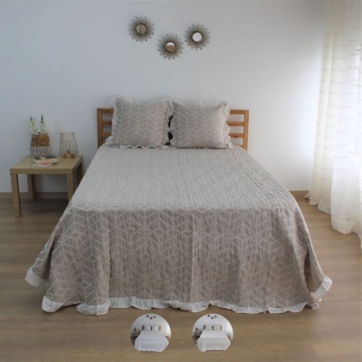 Cama com colcha bege e almofadas, mesas laterais, espelhos redondos na parede e cortina branca translúcida.