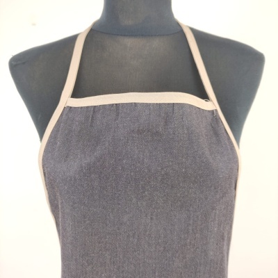 Avental cinzento escuro com bordas bege claro num manequim preto