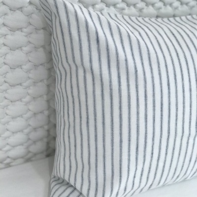 Travesseiro com fronha branca riscada em azul escuro e cabeça de cama acolchoada branca