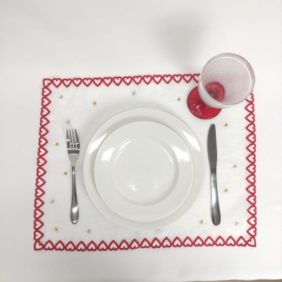 Conjunto de mesa com prato, talheres, guardanapo bordado e copo com base vermelha