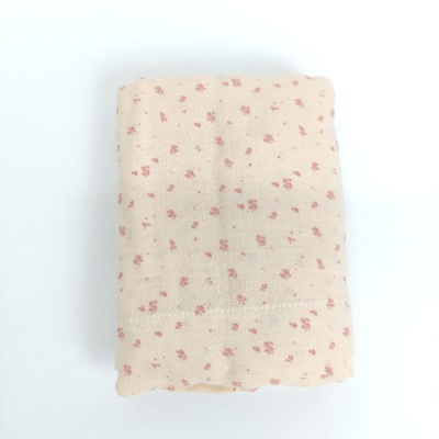 Toalha ou pano de algodão creme com flores vermelhas dobrado sobre fundo branco