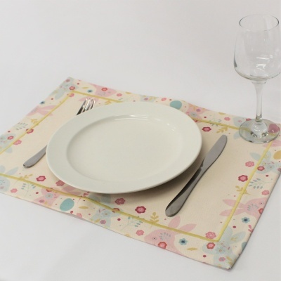 Conjunto de mesa com prato branco, talheres de metal, copo de vidro e guardanapo floral