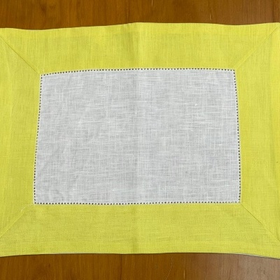 Jogo americano retangular branco e amarelo sobre mesa de madeira