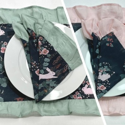 Toalhas de mesa e guardanapos com padrão de coelhos e flores em fundo azul escuro com bordas verdes e rosas