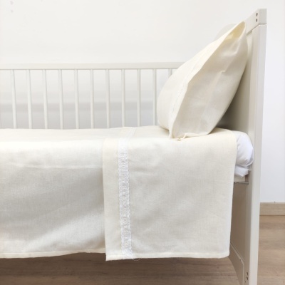 Cama branca com roupa de cama creme com detalhe de renda