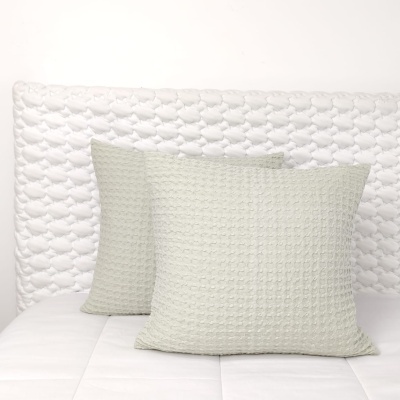 Três almofadas com padrões em cama branca