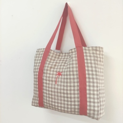 Mala xadrez castanho e branco com alças vermelhas e bordado de palmeira